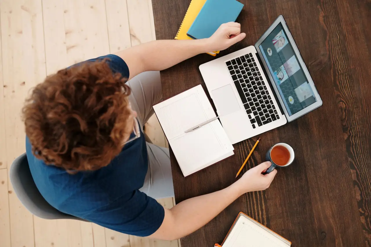 Personne au bureau avec un ordinateur portable, un carnet et une tasse